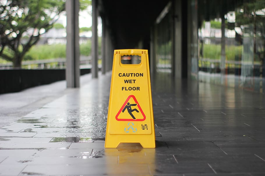 yellow-caution-wet-floor-signage-on-wet-pavement